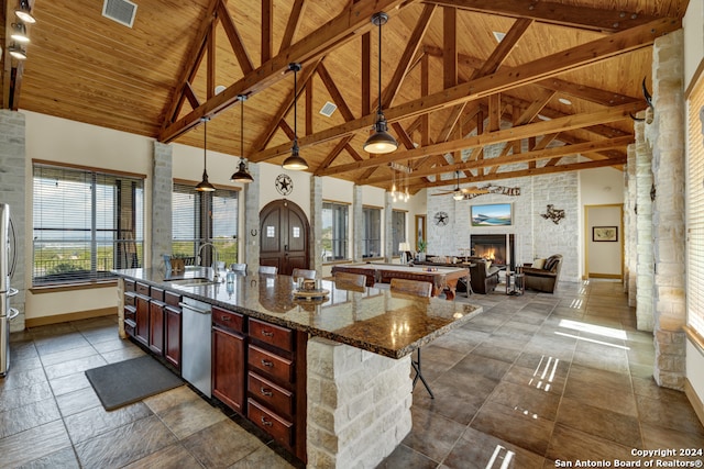 kitchen featuring pendant lighting, high vaulted ceiling, and a kitchen island with sink