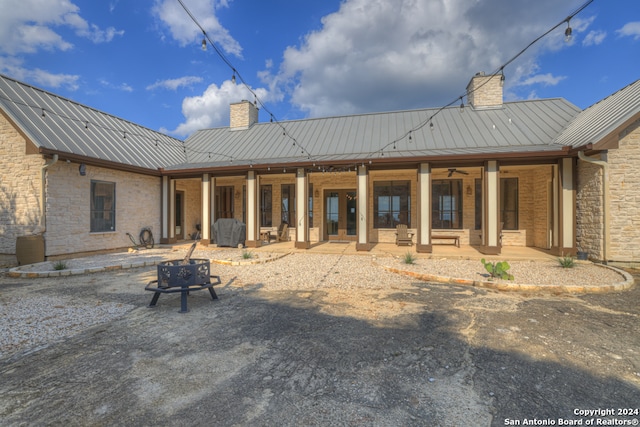 rear view of house with ceiling fan, a patio, and a fire pit