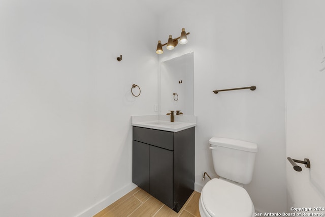 bathroom with toilet, vanity, and wood-type flooring