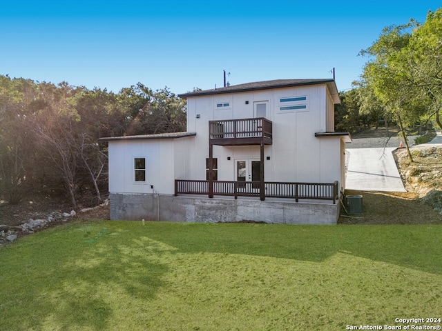 rear view of property featuring a balcony, a lawn, and central AC