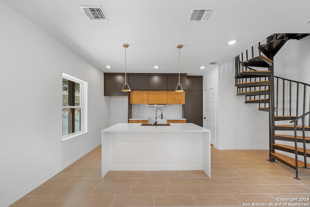 kitchen featuring a center island with sink, sink, and pendant lighting