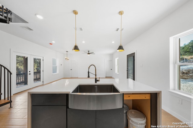 kitchen with sink, an island with sink, ceiling fan, pendant lighting, and light hardwood / wood-style flooring