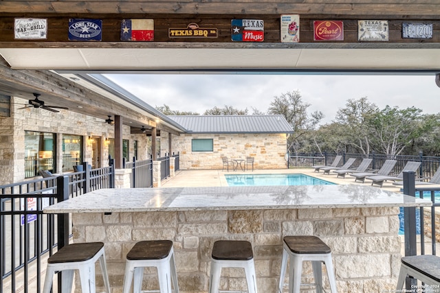 view of swimming pool with ceiling fan and exterior bar