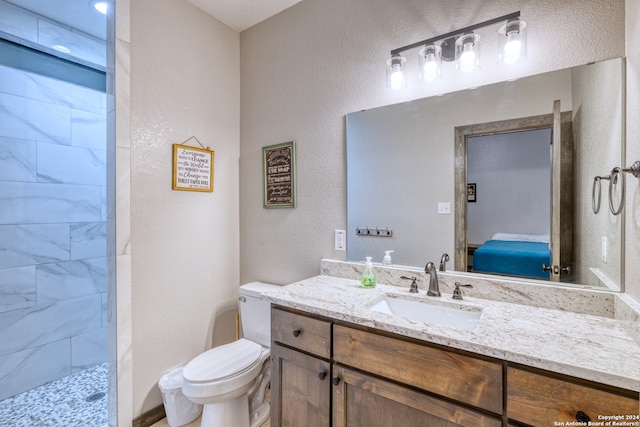 bathroom with vanity, toilet, and a tile shower