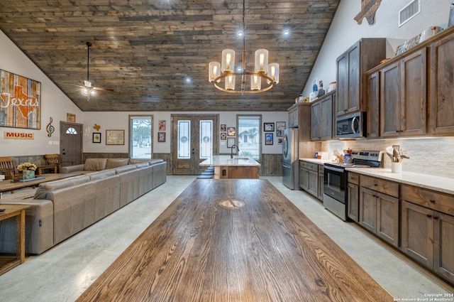 kitchen featuring high vaulted ceiling, dark brown cabinets, a center island with sink, appliances with stainless steel finishes, and ceiling fan with notable chandelier