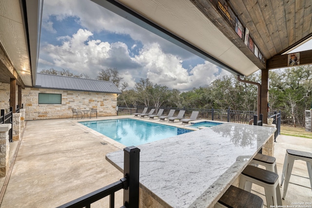 view of pool with an outdoor bar and a patio area