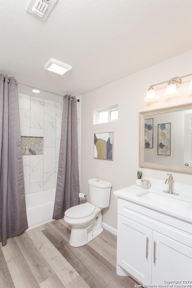 full bathroom with a textured ceiling, shower / bathtub combination with curtain, wood-type flooring, vanity, and toilet