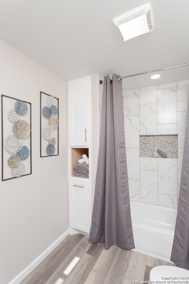 bathroom featuring hardwood / wood-style flooring and shower / bathtub combination with curtain