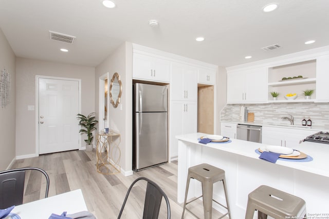 kitchen featuring light hardwood / wood-style flooring, white cabinets, a breakfast bar, and stainless steel appliances