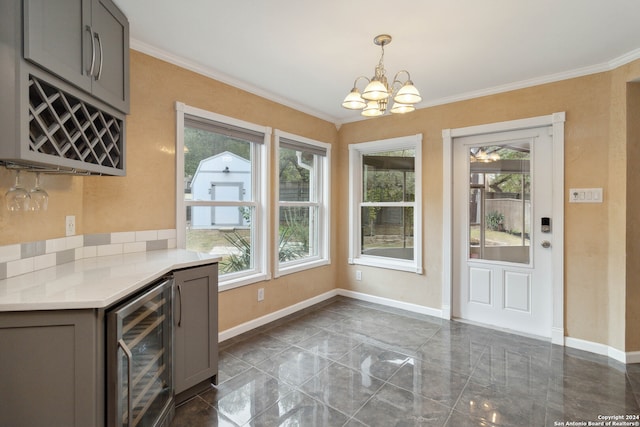 kitchen with pendant lighting, ornamental molding, beverage cooler, and gray cabinetry