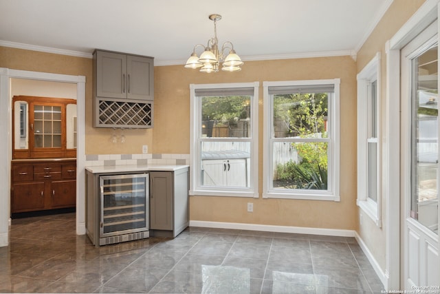 bar with gray cabinets, beverage cooler, a notable chandelier, and crown molding