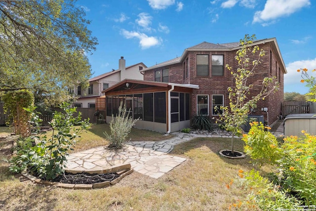 back of property with a patio area, a sunroom, and a yard