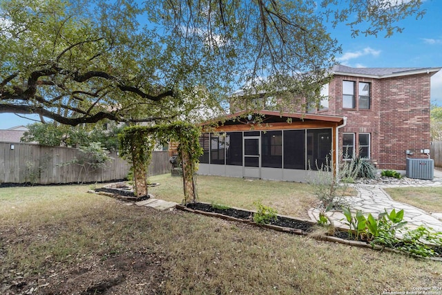 back of house with central AC unit, a lawn, and a sunroom