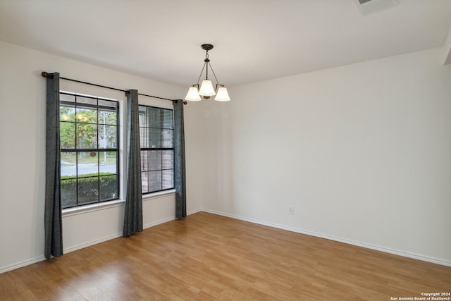 empty room featuring a chandelier and light hardwood / wood-style flooring