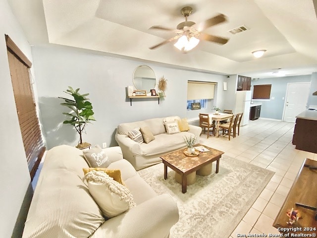 living room with ceiling fan, light tile patterned floors, and a raised ceiling