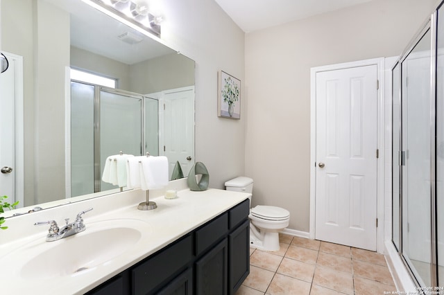 bathroom featuring vanity, a shower with shower door, tile patterned flooring, and toilet