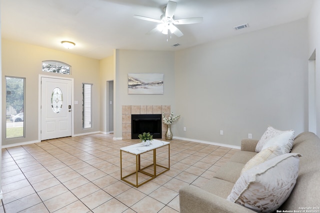 living room featuring a tile fireplace, light tile patterned floors, and ceiling fan