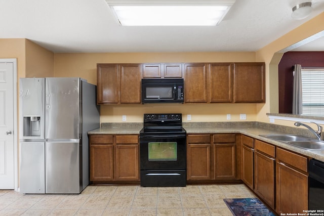 9002 Oakwood Park, San Antonio, TX 78254 - kitchen with black appliances, a sink, brown cabinets, and light tile patterned floors