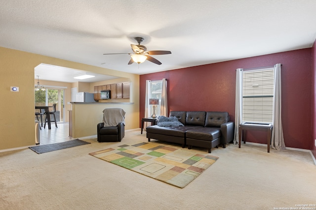 carpeted living room with a textured ceiling and ceiling fan with notable chandelier