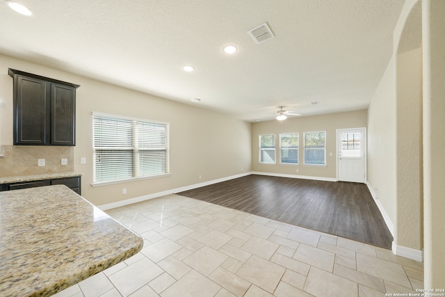 kitchen featuring light stone countertops, light hardwood / wood-style flooring, ceiling fan, and a textured ceiling