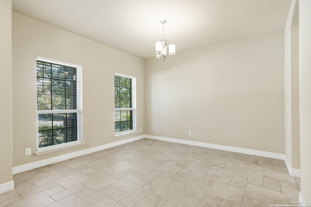 unfurnished room with a chandelier