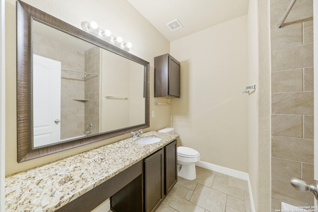 bathroom with tile patterned floors, vanity, toilet, and a tile shower