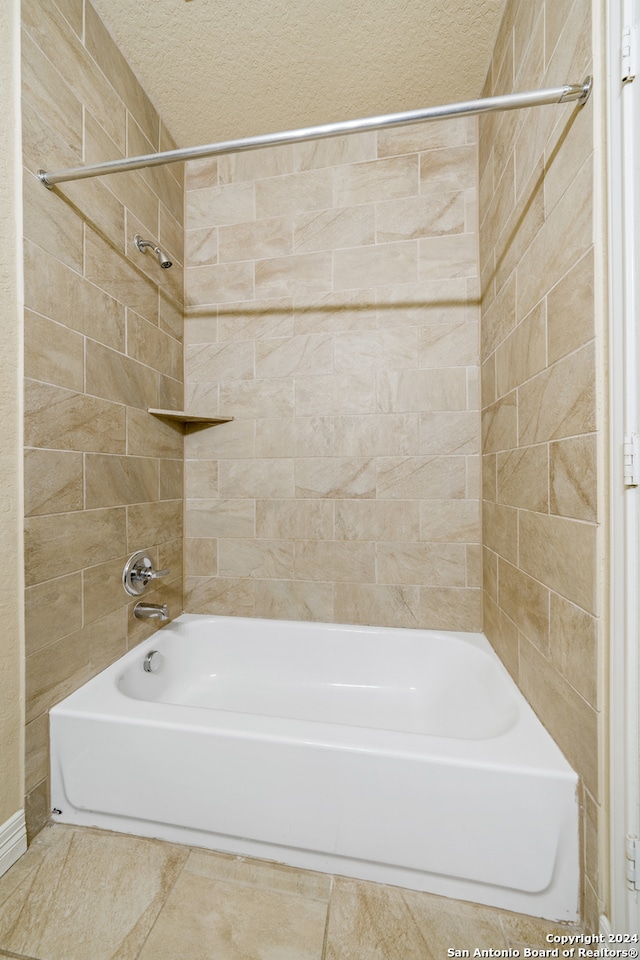 bathroom with tile patterned floors, a textured ceiling, and tiled shower / bath combo