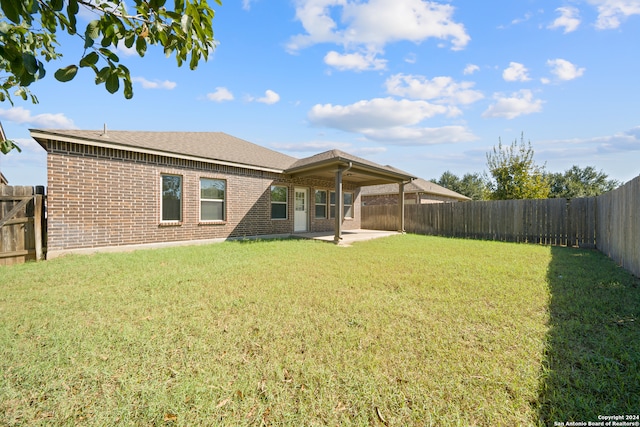 rear view of property featuring a yard and a patio area