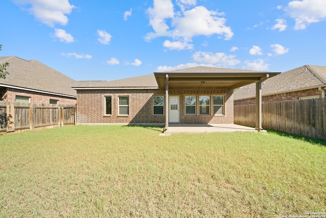 rear view of property featuring a lawn and a patio area