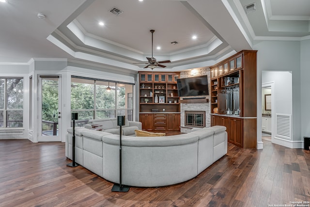 living room featuring ornamental molding, dark wood-type flooring, and a stone fireplace