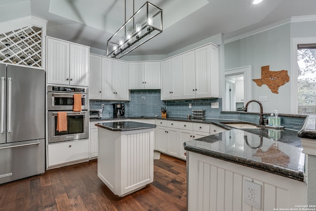 kitchen with stainless steel appliances, sink, kitchen peninsula, ornamental molding, and decorative light fixtures