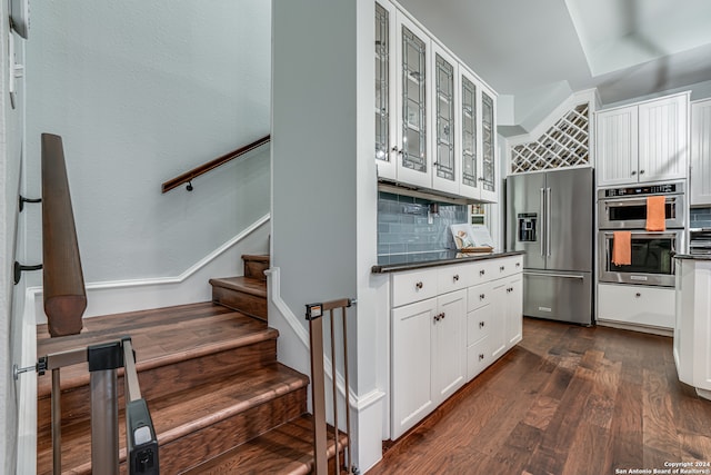 kitchen with dark hardwood / wood-style flooring, white cabinetry, appliances with stainless steel finishes, and tasteful backsplash