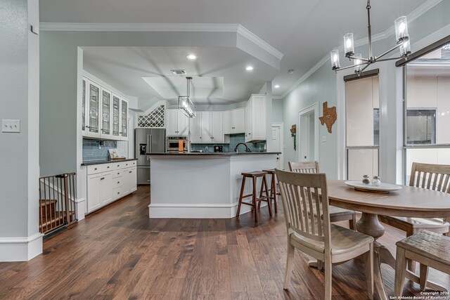 kitchen featuring stainless steel appliances, decorative light fixtures, backsplash, white cabinets, and dark wood-type flooring