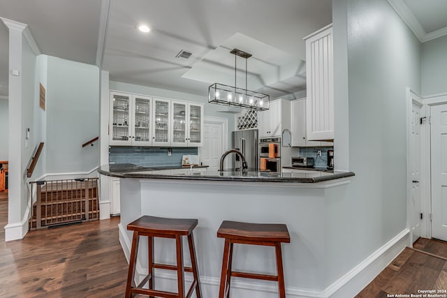 kitchen with tasteful backsplash, white cabinetry, decorative light fixtures, dark hardwood / wood-style flooring, and kitchen peninsula