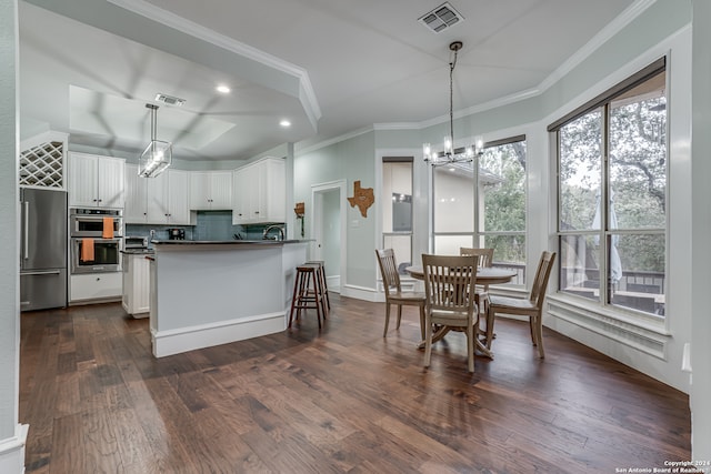 kitchen with stainless steel appliances, white cabinetry, pendant lighting, and dark hardwood / wood-style flooring