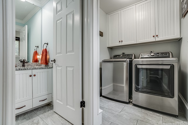 laundry area featuring ornamental molding, cabinets, washer and clothes dryer, and sink