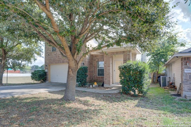 view of property hidden behind natural elements with central AC unit and a garage