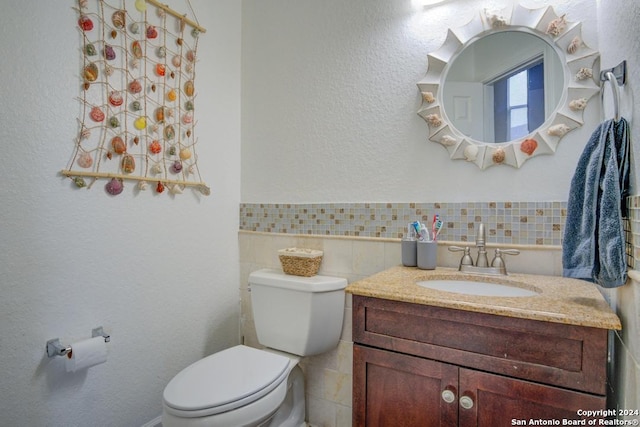 bathroom featuring vanity, tile walls, and toilet