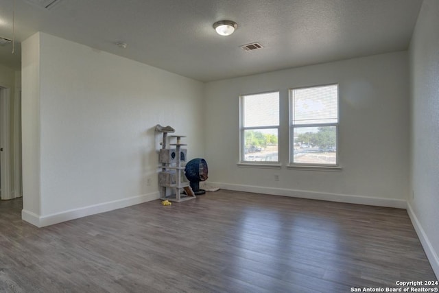 unfurnished room featuring a textured ceiling and dark hardwood / wood-style flooring