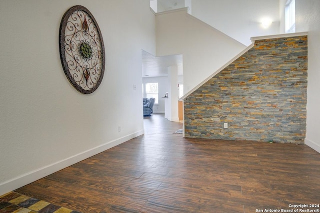 unfurnished living room with dark hardwood / wood-style flooring and a towering ceiling