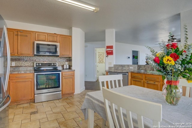 kitchen with decorative backsplash, kitchen peninsula, a textured ceiling, stainless steel appliances, and ceiling fan