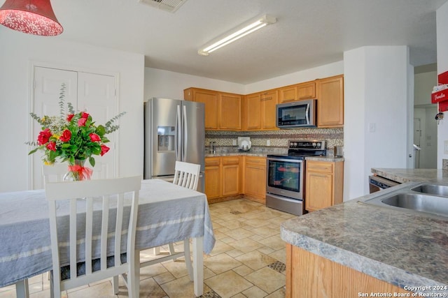 kitchen with tasteful backsplash, sink, and appliances with stainless steel finishes