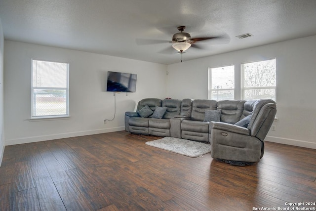 living room featuring dark hardwood / wood-style floors, ceiling fan, and a textured ceiling