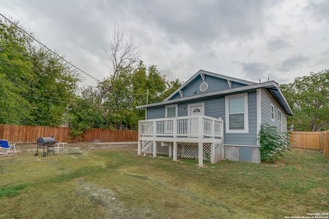 back of house with a wooden deck and a yard