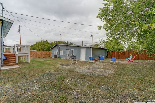 view of yard with central AC, a fire pit, and a wooden deck