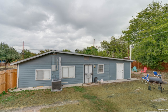 back of house with central AC unit and a yard