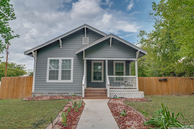 bungalow-style home featuring covered porch and a front yard