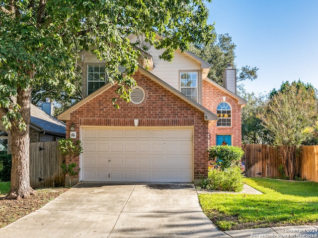 view of property featuring a garage and a front lawn