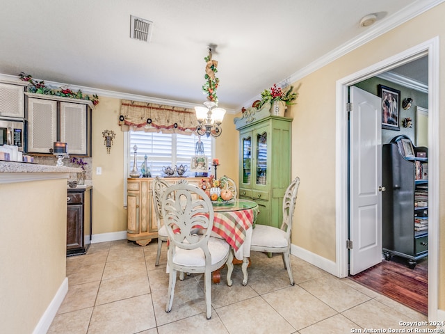 dining room with a chandelier, light tile patterned floors, and ornamental molding