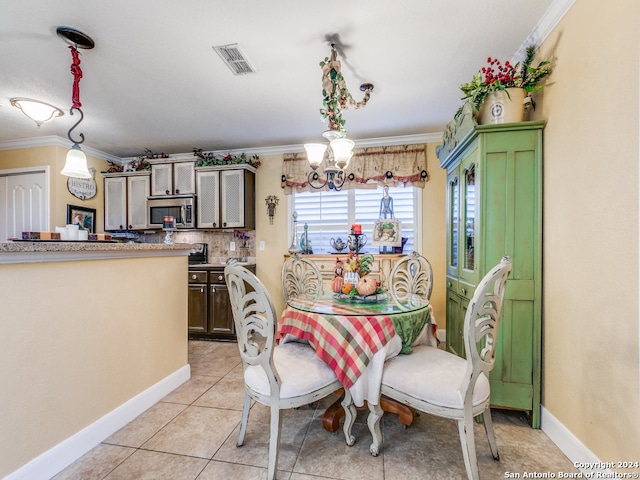 tiled dining space featuring a notable chandelier and ornamental molding